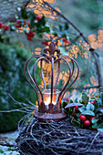 Tealight in rusty decorative crown on top of wreath on table outside