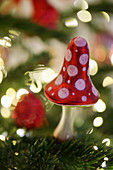 Christmas tree decoration in shape of fly agaric mushroom surrounded by sparkling lights