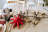 Weihnachtstisch mit rotem Papierstern, Lärchenzweigen und Kerzen