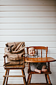 Laughing baby in old high chair next to a kangaroo