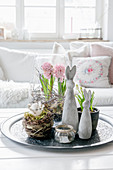 Osterhasen, ein Nest und Frühlingsblumen im Wohnzimmer