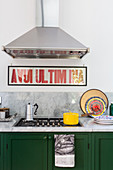 Extractor hood and lettering above gas cooker in green kitchen