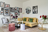 Yellow velvet sofa below gallery of photographs on wall