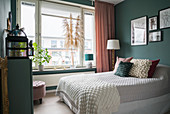 Double bed in guest room with dark matt green walls