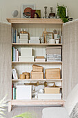 Storage boxes in cupboard with fabric-covered doors made from old windows