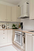 Pale, L-shaped fitted kitchen