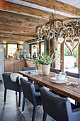 Upholstered chairs around rustic dining table in open-plan country-house kitchen