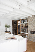 Rustic bedroom with white ceiling beams and stone wall