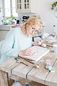 Woman seated at dining table making Easter pendants from modelling clay