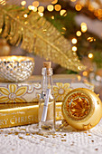 Wish list in tiny bottle surrounded by golden Christmas decorations