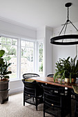 Dining table with black rattan armchairs, above it ring-shaped pendant lamp