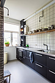 Fitted kitchen with dark cabinets and tiled wall
