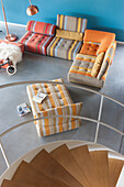 View from above of colorful striped sofa, spiral staircase and concrete floor