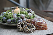 Candle lantern in wreath of hydrangeas, globe thistles and snail shells