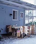 Sitzplatz auf überdachter Terrasse am blauen Holzhaus im Winter
