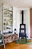 A cast iron stove, firewood and a wooden shelf in a dining room