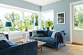 Blaue Sofagarnitur im Wohnzimmer mit Fensterfront