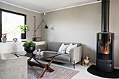 Graues Sofa und Kaminofen im Wohnzimmer mit grauer Wand