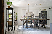 Vitrine und Holztisch mit grau lackierten Stühlen in skandinavischem Esszimmer