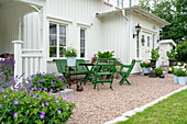 Terrassenplatz mit grünen Gartenmöbeln vor Holzhaus