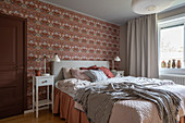 A double bed in a wallpapered bedroom