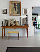 Stool at console table covered with pictures and sculptures in artist's house