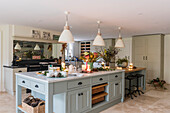 Cremefarbene Pendelleuchten über Kücheninsel mit Marmorplatte in Landhausküche