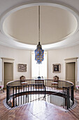 Circular galleried landing hung with a collection of colourful 19th and 20th century paintings
