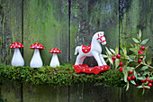 Fly agaric mushroom and rocking horse on moss garland, butcher's broom branch with berries
