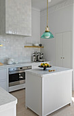 Island counter with marble top in white kitchen with glazed tiles