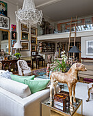 Artwork and collectables with 1920s glass chandelier in living room with glass mezzanine
