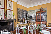 Framed hand painted warriors hang above a marble mantlepiece in dining room with 18th century french dining table and hand painted french chairs