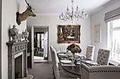 Deer's head above fireplace in dining room with glass chandelier