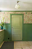 Green door, matching wood panelling and wallpaper in the kitchen