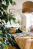 Zimmerpflanzen und Doppelbett im Schlafzimmer in Gelb- und Grüntönen