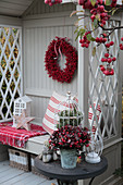 Weihnachtlich dekorierte Philosophenbank mit rotem Beerenkranz, Holzstern und dekoriertem Tischchen