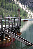 Holzsteg mit Leiter und Booten am See