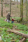 Mother and child in spring woods surrounded by wood anemones and lesser celandines