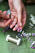 Woman threading lilac florets onto fine silver wire
