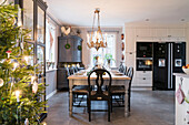 Rustic, set dining table in kitchen-dining room, Christmas tree with lights in foreground