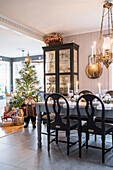 Rustikaler, gedeckter Esstisch, Vitrinenschrank und beleuchteter Weihnachtsbaum in Wohnküche