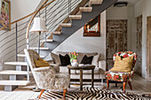 Upholstered furniture on zebra-skin rug in living area with staircase