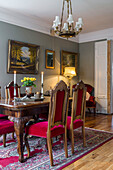 Antique dining table and chairs and paintings in drawing room with grey-green walls