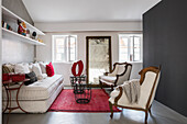Antique armchairs and couch in living room with red accents
