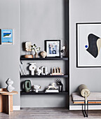 Shelves with decorative objects and framed pictures on grey wall