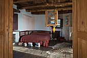 Doppelbett und Zebrafellteppich in rustikalem Schlafzimmer mit Holzbalkendecke