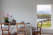 Esstisch mit rustikalen Stühlen im Zimmer mit weiß lackierter Holzverkleidung