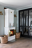 White, Swedish tiled stove next to glass doors with black frame