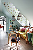 Comfortable sofa with scatter cushions below birdcages in attic room