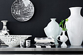 White vases, bowls and tableware against black wall